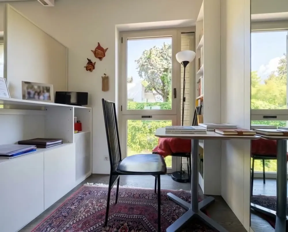 A study corner with a desk by a window onto greenery (frame from an AI-animated video).